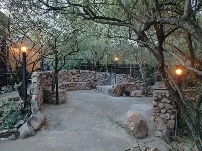 a park with a stone wall and trees and lights at 2694 Marloth Park Family Villa in Marloth Park