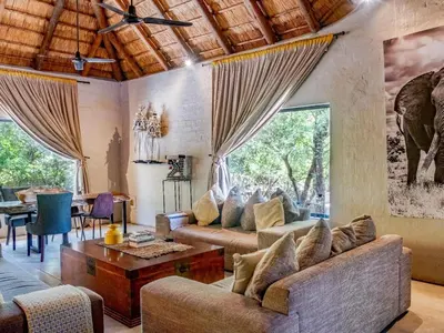 a living room with two couches and a table at Croc Orvyll's Kruger Lodge in Marloth Park