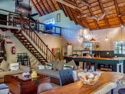 a living room with a staircase and a table at Croc Orvyll's Kruger Lodge in Marloth Park