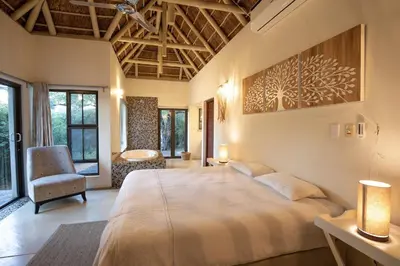 a bedroom with a large bed and a chair at Villa Blaaskans in Hoedspruit
