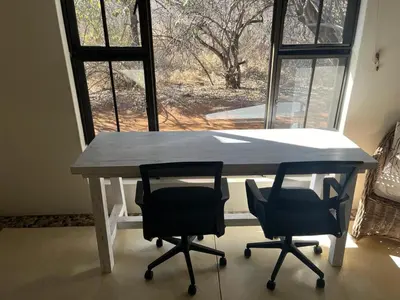 a table with two chairs in a room with a window at Villa Blaaskans in Hoedspruit