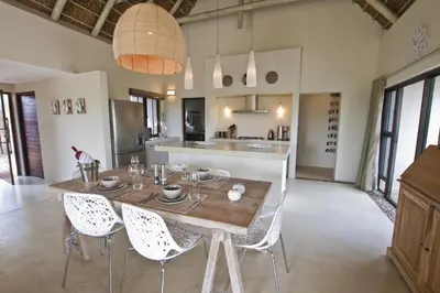 a kitchen and dining room with a wooden table and chairs at Villa Blaaskans in Hoedspruit