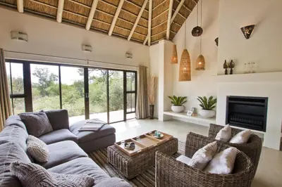 a living room with a couch and chairs and a fireplace at Villa Blaaskans in Hoedspruit