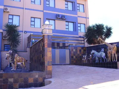 a building with statues of giraffes and zebras in front at The Empire Hotel in Vendaland