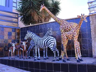a group of giraffes and zebras standing next to a wall at The Empire Hotel in Vendaland