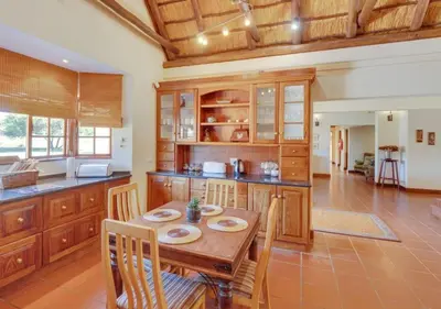 a large kitchen with a wooden table and chairs at Zebula 1 Pela Lodge, 4-bedroom house in Warmbaths
