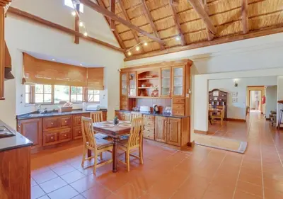 a kitchen with wooden cabinets and a table and chairs at Zebula 1 Pela Lodge, 4-bedroom house in Warmbaths