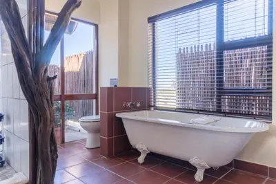a bathroom with a tub and a toilet and a window at Zebula 1 Pela Lodge, 4-bedroom house in Warmbaths