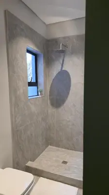 a bathroom with a shower with a toilet and a window at GrootBoom Guest Rooms in Pretoria
