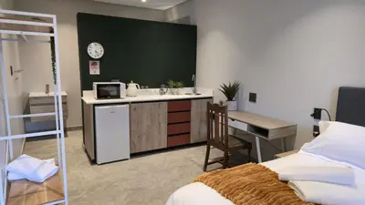 a room with a bedroom with a desk and a bed at GrootBoom Guest Rooms in Pretoria