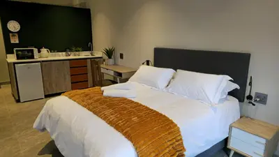 a bedroom with a large bed with white sheets and pillows at Grootboom Guest Rooms in Pretoria