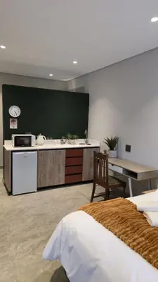 a room with a kitchen and a table and a bed at Grootboom Guest Rooms in Pretoria