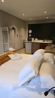 a large bed with white pillows in a room at Grootboom Guest Rooms in Pretoria