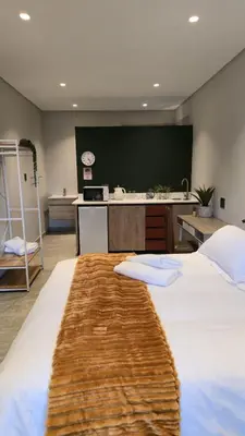 a bedroom with a large white bed with a desk at Grootboom Guest Rooms in Pretoria