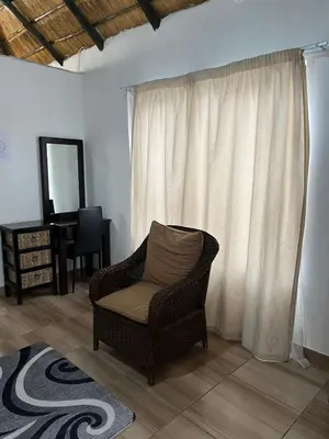 a living room with a chair and a mirror at Aero Ensuites- OR Tambo in Kempton Park