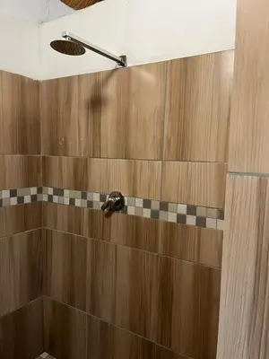 a bathroom with a shower with wooden walls and aaucet at Aero Ensuites- OR Tambo in Kempton Park