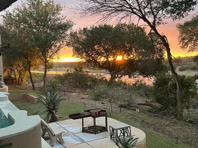 a patio with a table and chairs at sunset at Imberbe Private Lodge in Hectorspruit