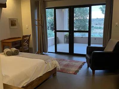 a bedroom with a bed and a chair and a window at Imberbe Private Lodge in Hectorspruit