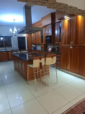 a kitchen with wooden cabinets and a island with stools at Aaybee for Four in Midrand