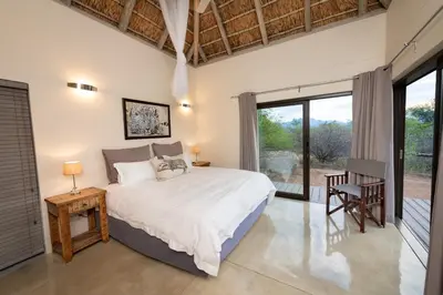 a bedroom with a bed and a large window at Villa Marula in Hoedspruit