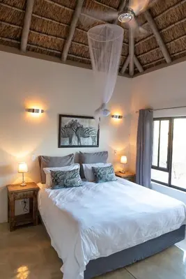 a bedroom with a large white bed with two lamps at Villa Marula in Hoedspruit