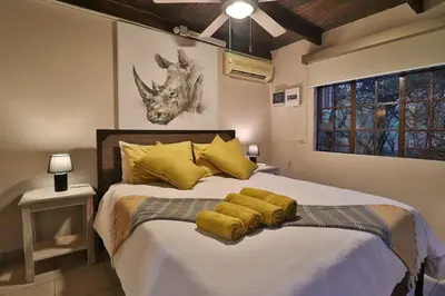 a bedroom with a large bed with yellow pillows at Qëtesia- Oasis of tranquility in Marloth Park