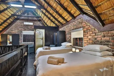 a bedroom with two beds and a brick wall at Qëtesia- Oasis of tranquility in Marloth Park