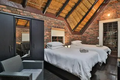 two beds in a room with a brick wall at Qëtesia- Oasis of tranquility in Marloth Park