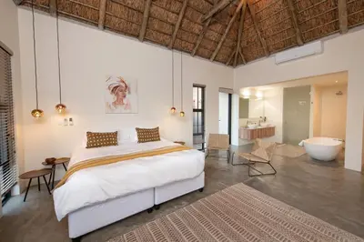 a bedroom with a large bed and a bath tub at Villa Scarabee in Hoedspruit