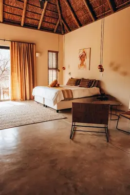 a bedroom with a large bed and a table at Villa Scarabee in Hoedspruit