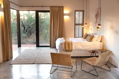 a bedroom with a bed and a table and chairs at Villa Scarabee in Hoedspruit