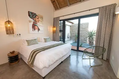 a bedroom with a large bed and a large window at Villa Scarabee in Hoedspruit