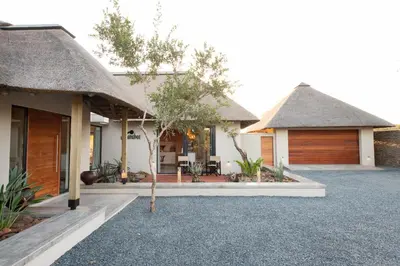 a house with a thatched roof and a garage at Villa Scarabee in Hoedspruit