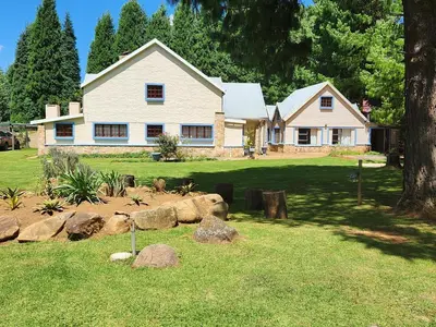 a white house with rocks in front of it at Stonefly Cottages in Dullstroom