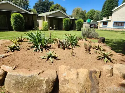 a garden with plants and rocks in a yard at Stonefly Cottages in Dullstroom