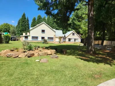 a white house with rocks in front of it at Stonefly Cottages in Dullstroom