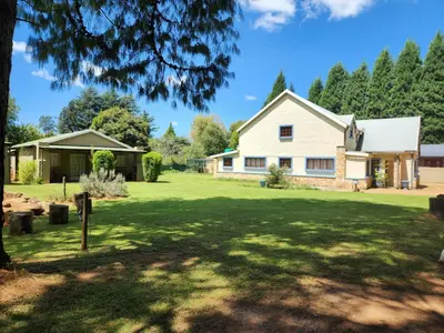 a house on a lawn with a tree at Stonefly Cottages in Dullstroom