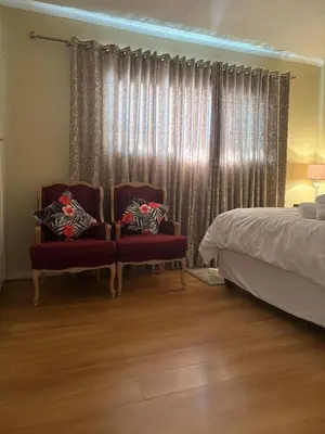 a bedroom with a bed and two chairs in front of a window at Top Building in Pretoria