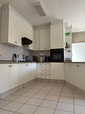 a kitchen with white cabinets and a tile floor at Top Building in Pretoria