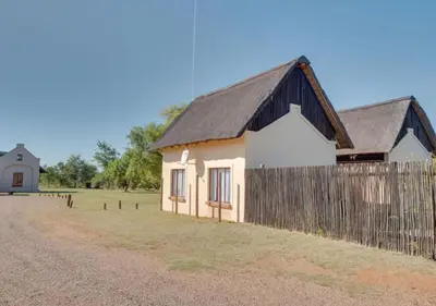 a small house with a fence next to a field at Zebula 1 Pela Lodge, 6 bedrooms in Warmbaths