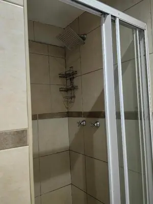a shower stall with a glass door with a shower at EasyStay Hideaway in Pretoria