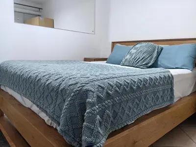 a bed with a gray blanket and blue pillows at EasyStay Hideaway in Pretoria