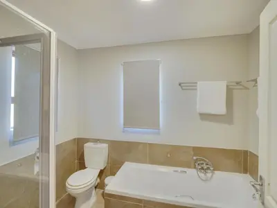 a bathroom with a tub and a toilet and a sink at Zebula 1 Pela Lodge, 2-bedroom cottage in Warmbaths