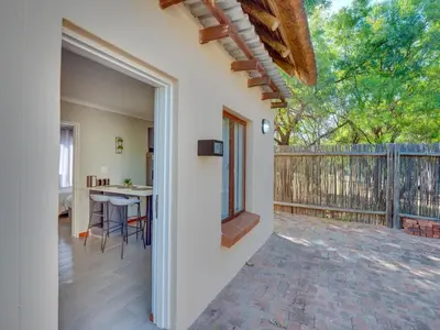 an open door to a patio with a table and a fence at Zebula 1 Pela Lodge, 2-bedroom cottage in Warmbaths