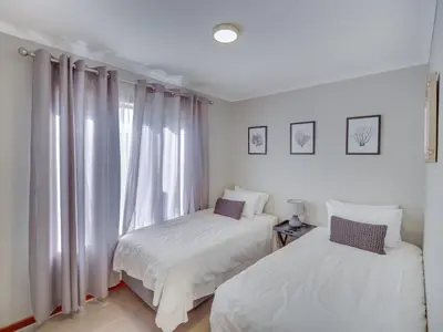two beds in a room with a window at Zebula 1 Pela Lodge, 2-bedroom cottage in Warmbaths