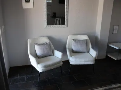 two white chairs sitting in a room with a mirror at Malembe Lodge in Midrand