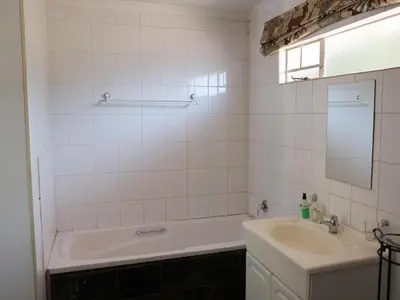 a white bathroom with a tub and a sink at Malembe Lodge in Midrand