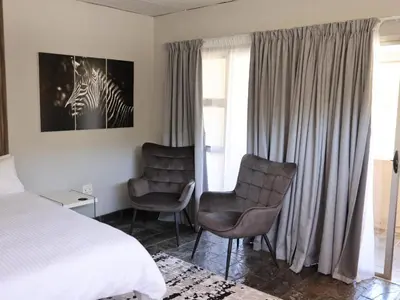 a hotel room with a bed and two chairs at Malembe Lodge in Midrand