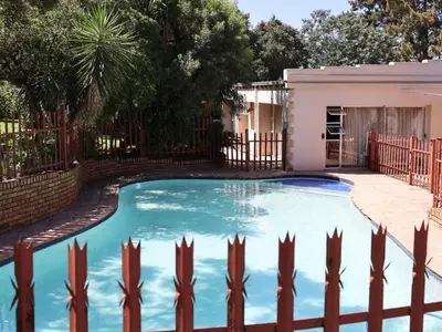 a swimming pool in a yard with a fence at Malembe Lodge in Midrand