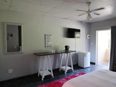 a room with a table with a mirror and a bed at Malembe Lodge in Midrand